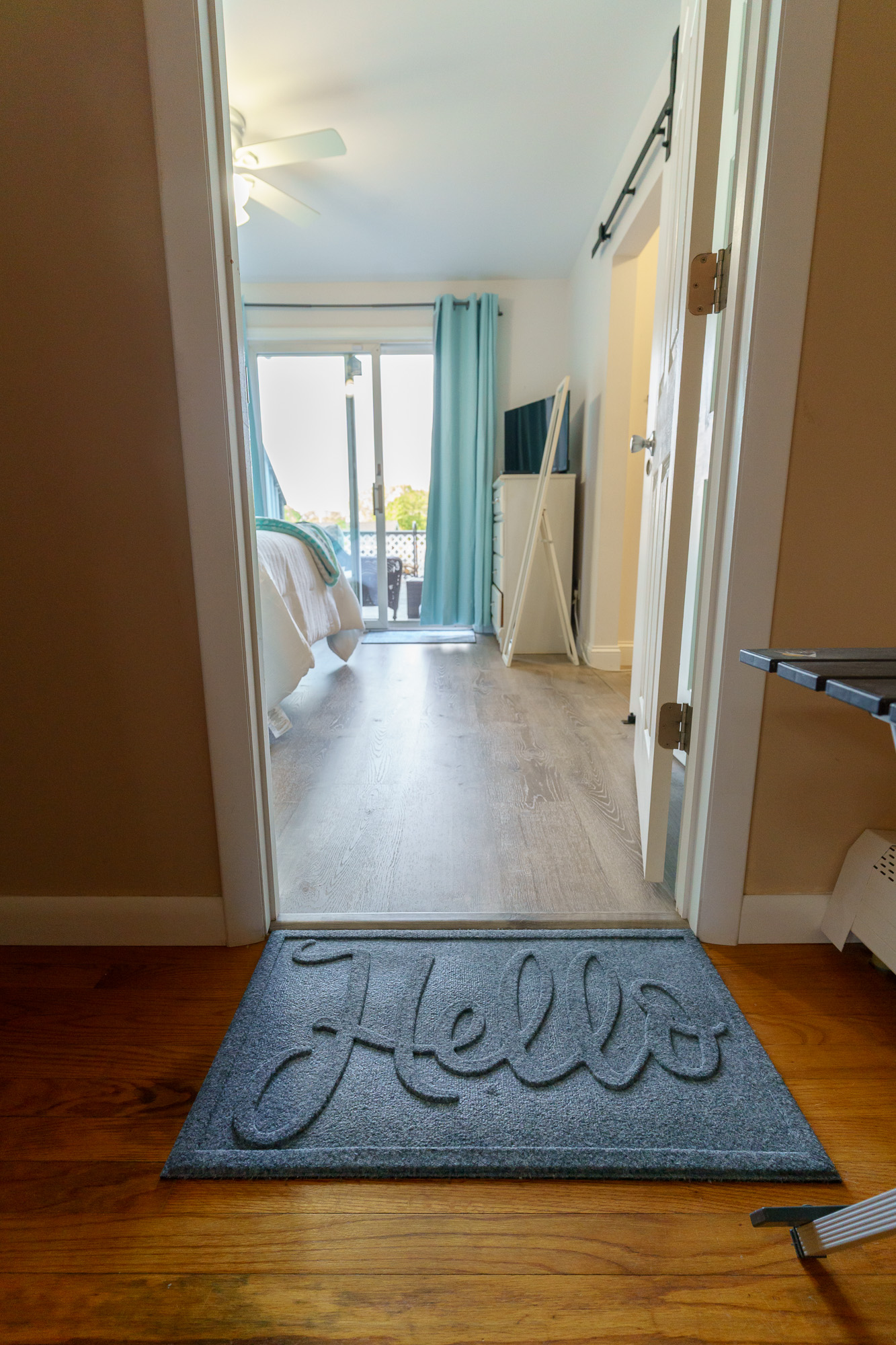 Hallway leading toward bedroom with Hello doormat