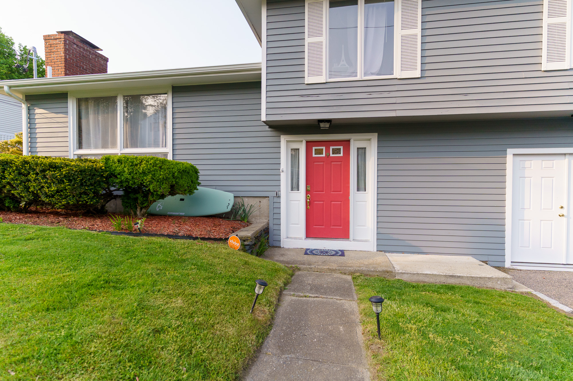 Front exterior of the home with red door and manicured lawn